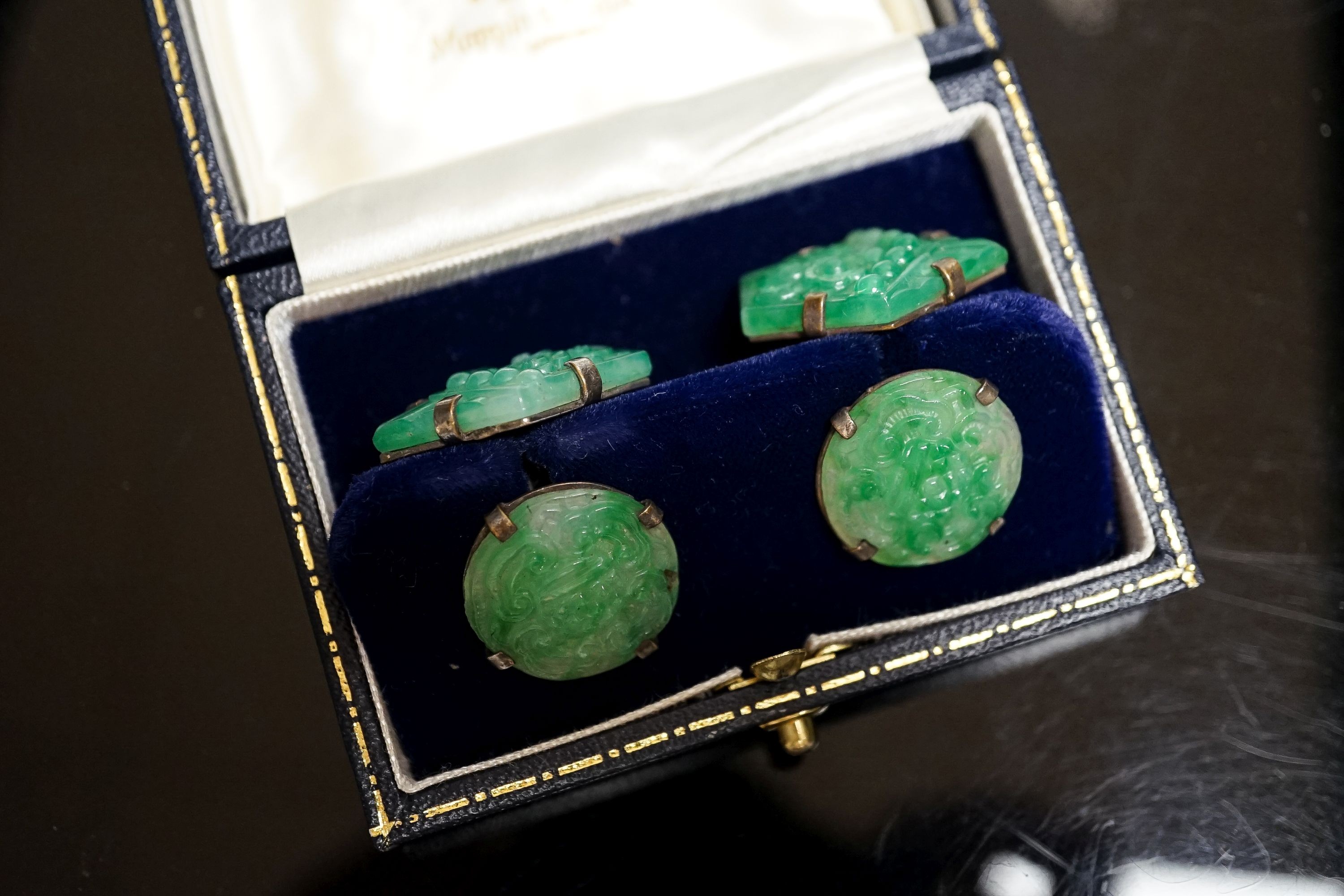 A pair of white metal mounted carved jade cufflinks, largest panel approx. 25mm.